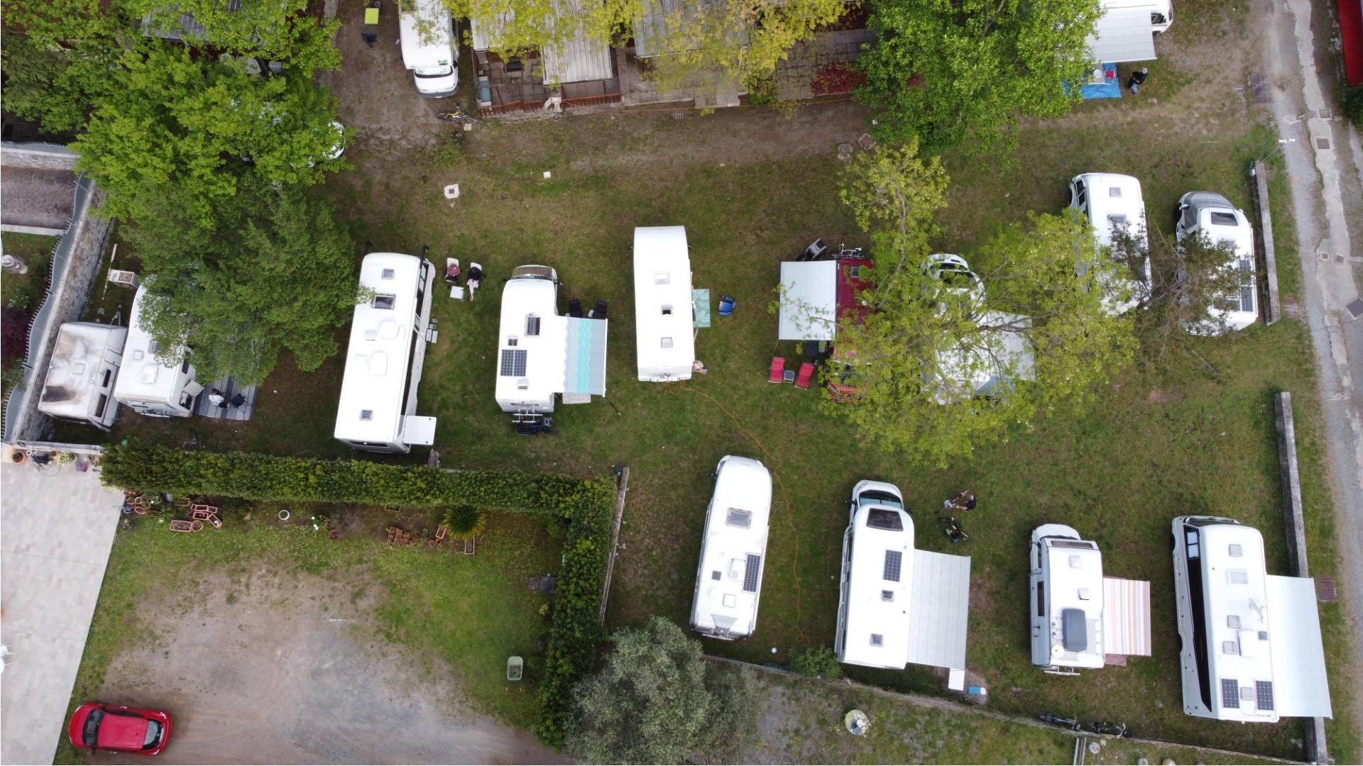 Luftaufnahme eines Campingplatzes mit geparkten Wohnmobilen und Wohnwagen.