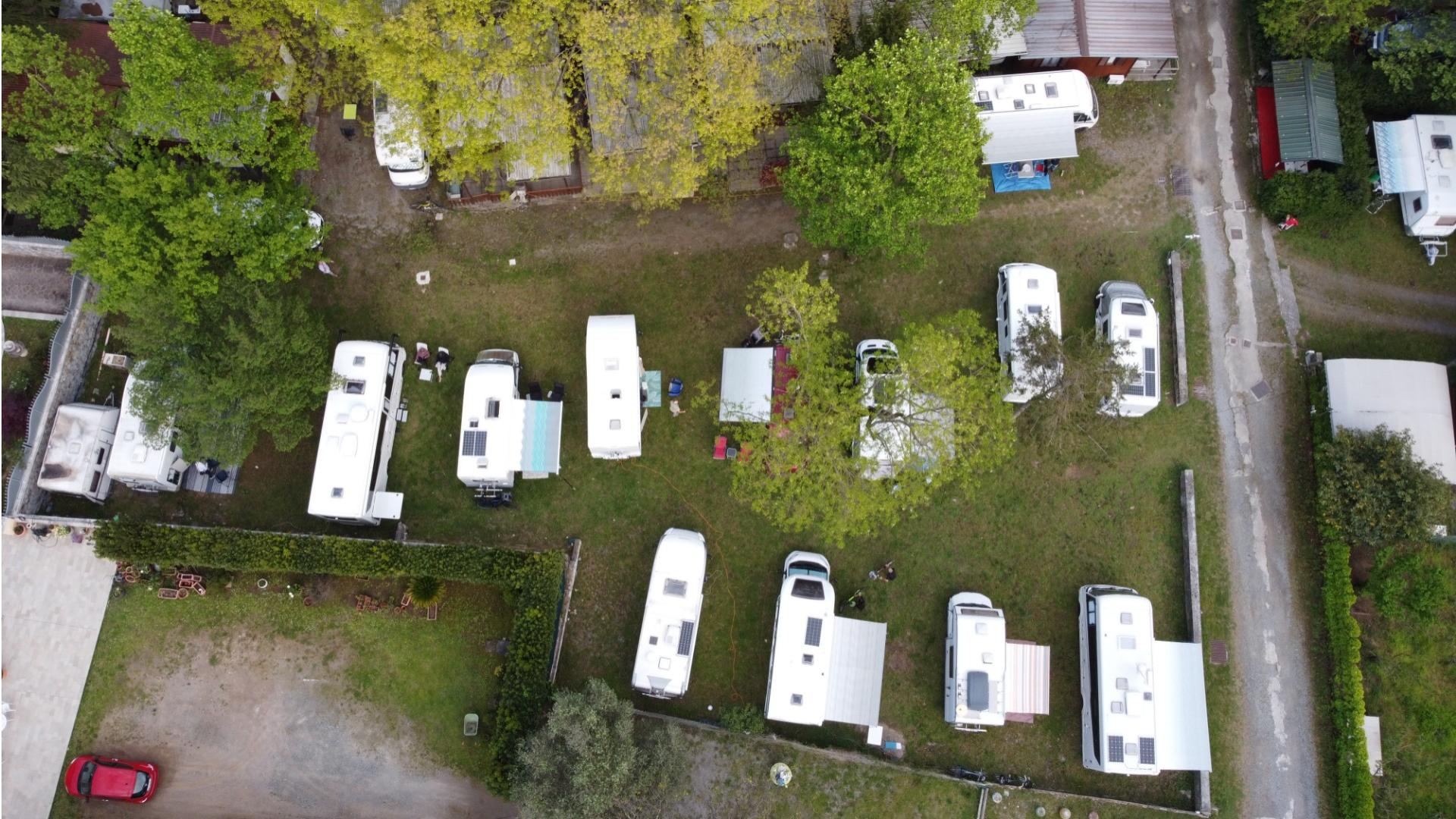 Aerial view of RVs parked in a green campsite with trees.