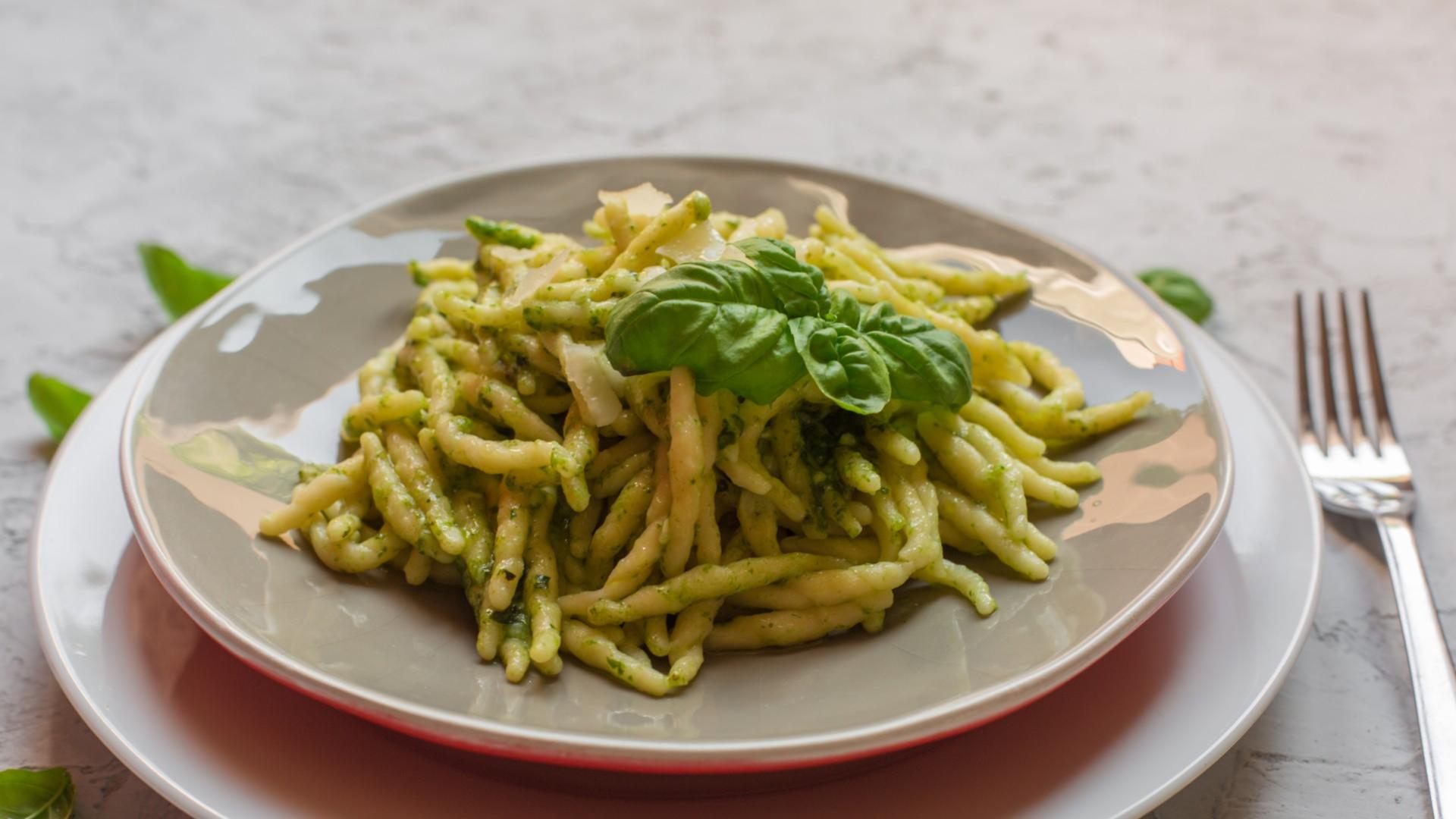 Piatto di trofie al pesto con basilico fresco.