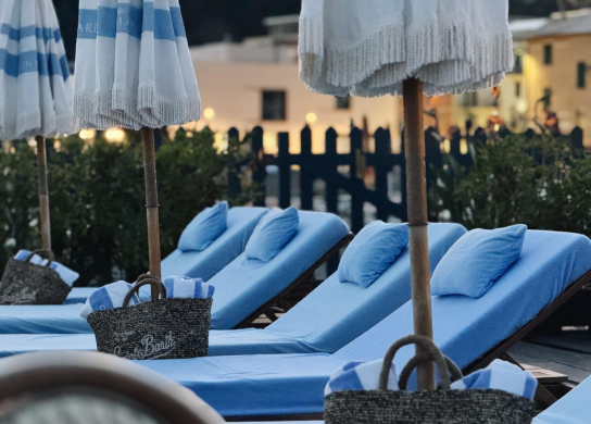 Blue loungers with umbrellas and bags in a relaxing setting.