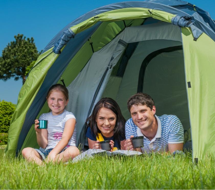 Famille heureuse en camping, profitant d'une boisson dans la tente.