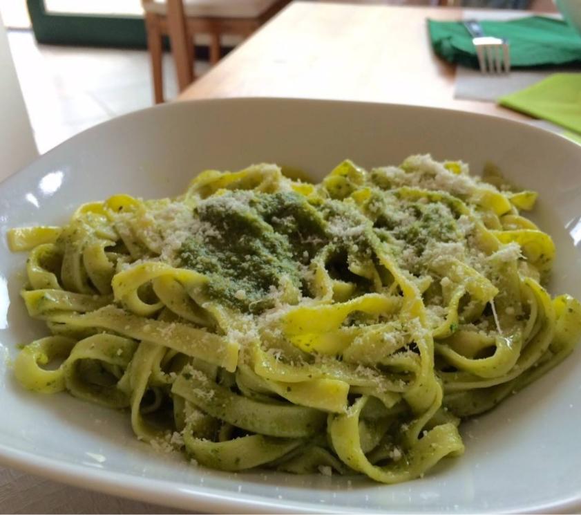 Tagliatelles au pesto avec parmesan dans une assiette blanche.