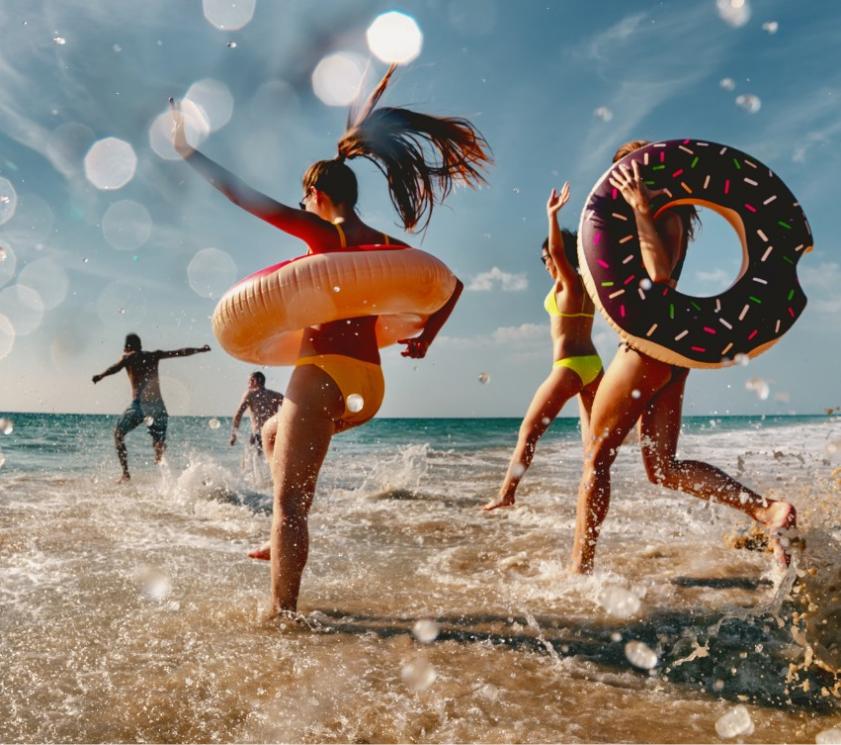 Menschen haben Spaß am Strand mit aufblasbaren Ringen.