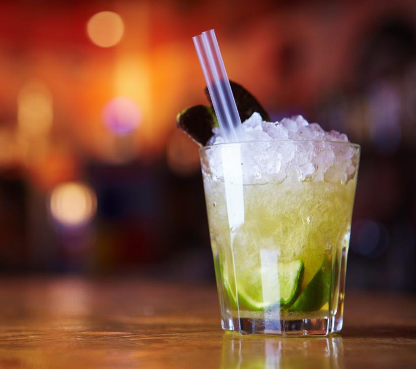 Cocktail with lime, crushed ice, and double straw in a clear glass.