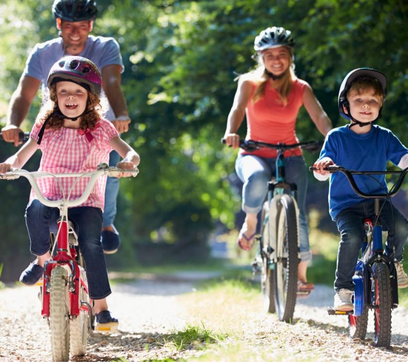 Familie fährt Rad auf einem Waldweg.