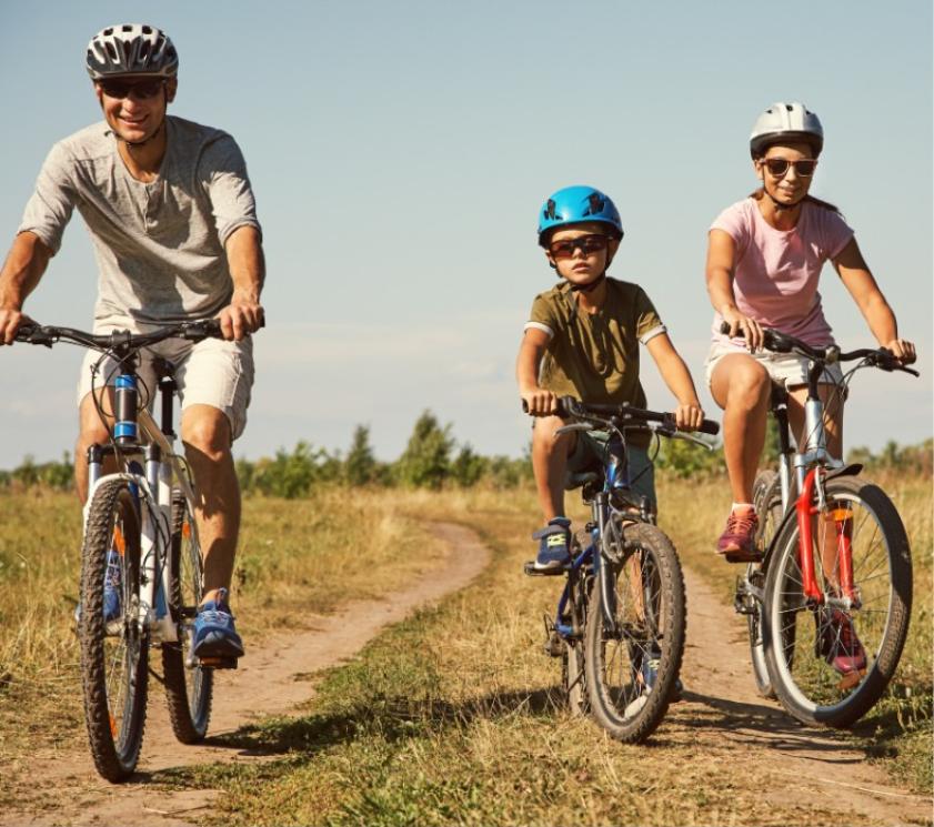Familie fährt Fahrrad auf einem Weg an einem sonnigen Tag.