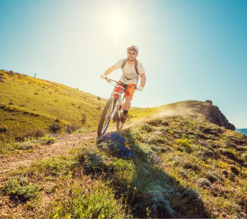 Cyclist on a mountain trail under the bright sun.